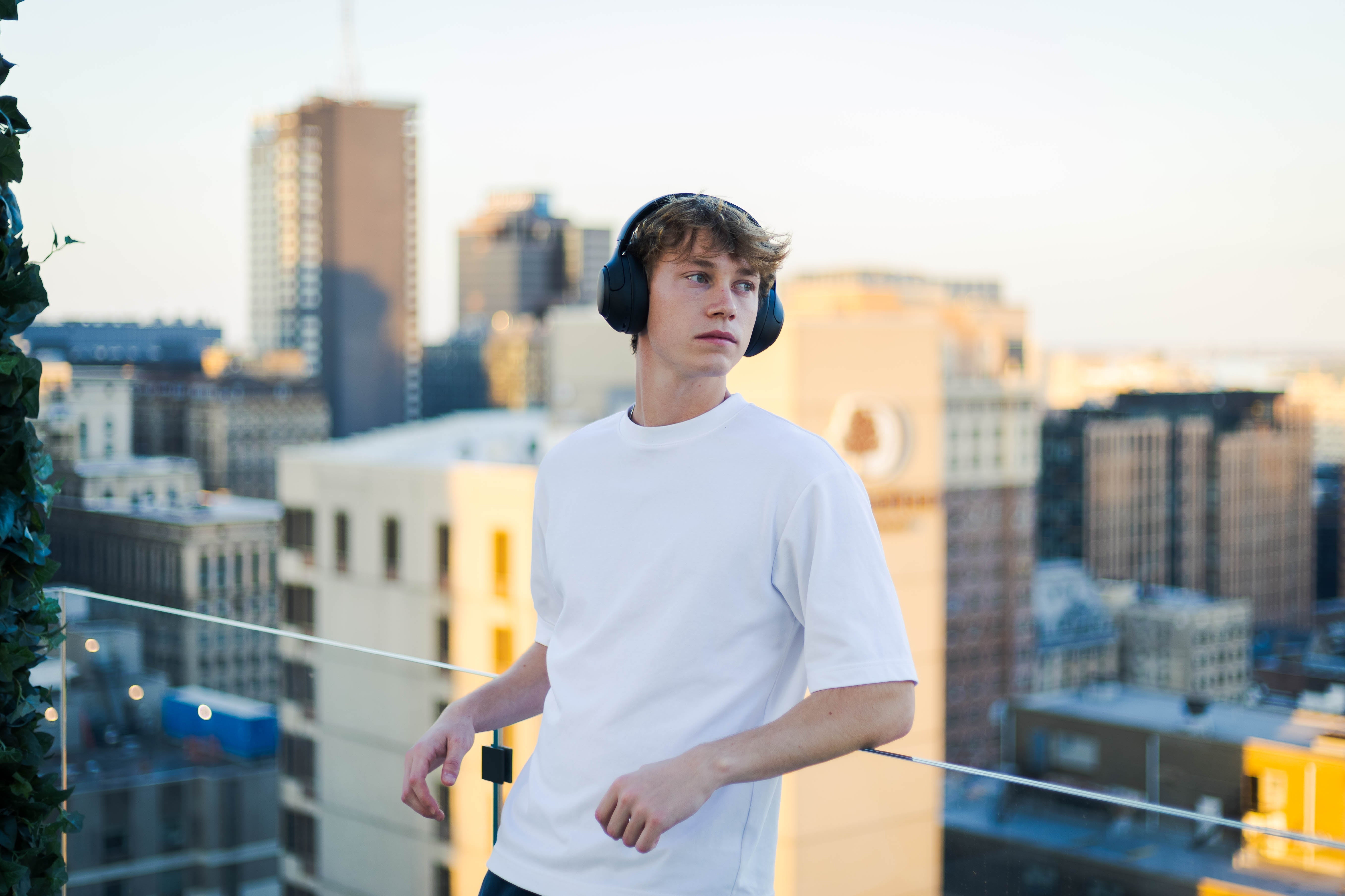 Junger Mann mit kabellosen Over-Ear-Kopfhörern auf Dachterrasse – Reparatur-Tipp für einseitigen Sound.
