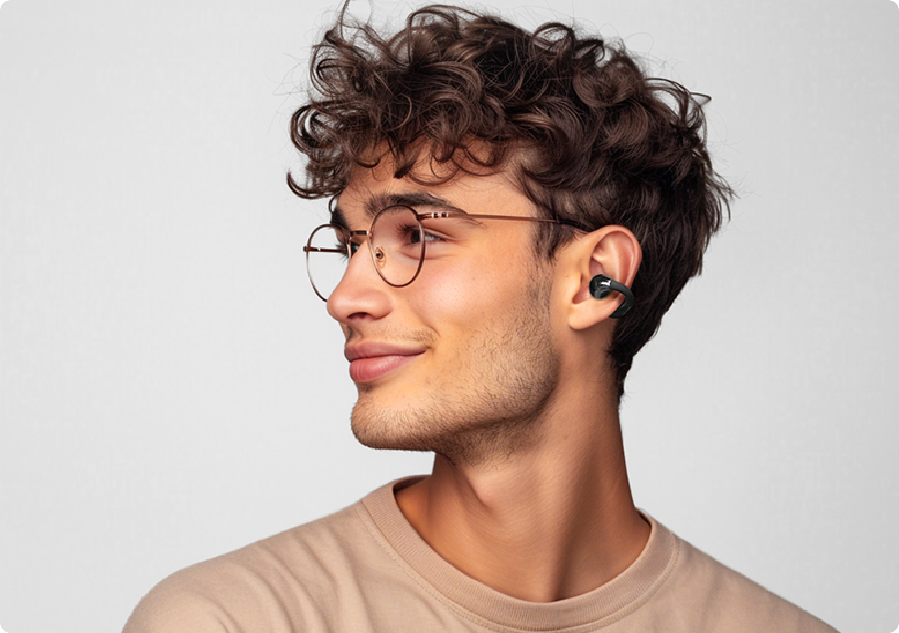 Giovane uomo con occhiali e auricolari wireless di profilo.