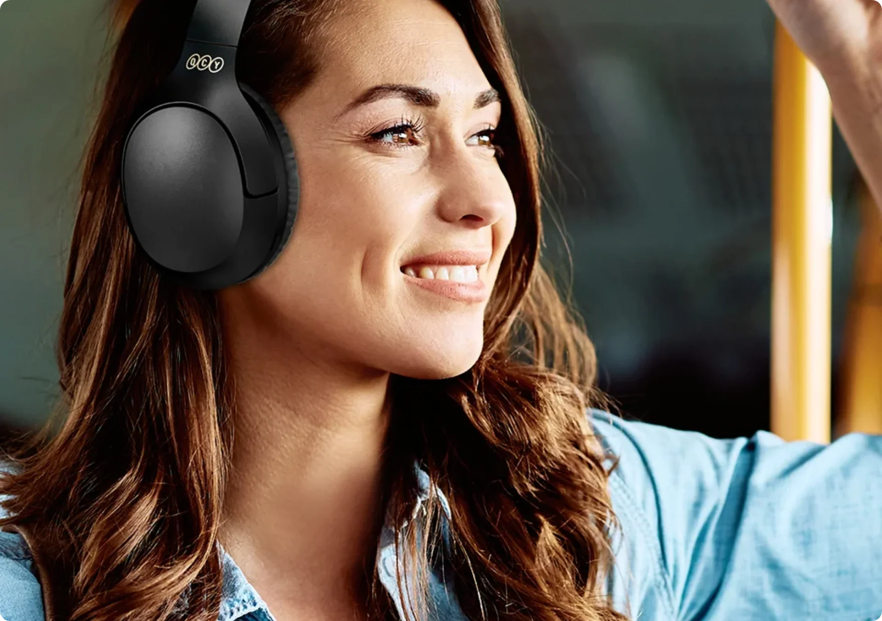 Donna con cuffie over-ear nere che sorride sull'autobus.