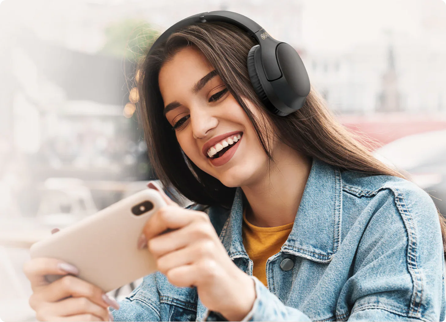 Donna sorridente con cuffie wireless e smartphone.