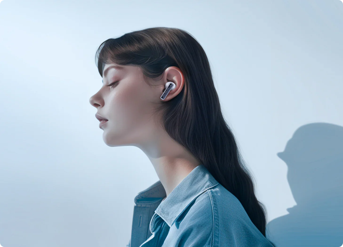 Donna con cuffie Bluetooth bianche in giacca di jeans, vista laterale