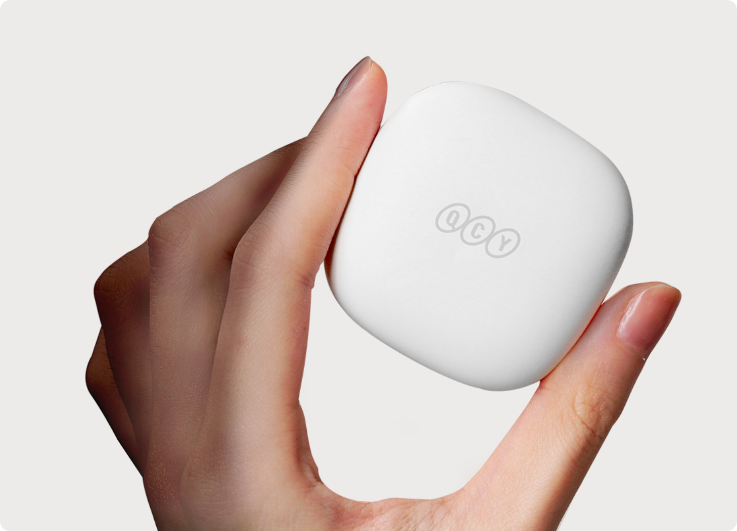 Scatola bianca per auricolari QCY in mano, design minimalista con logo, ideale per cuffie wireless.