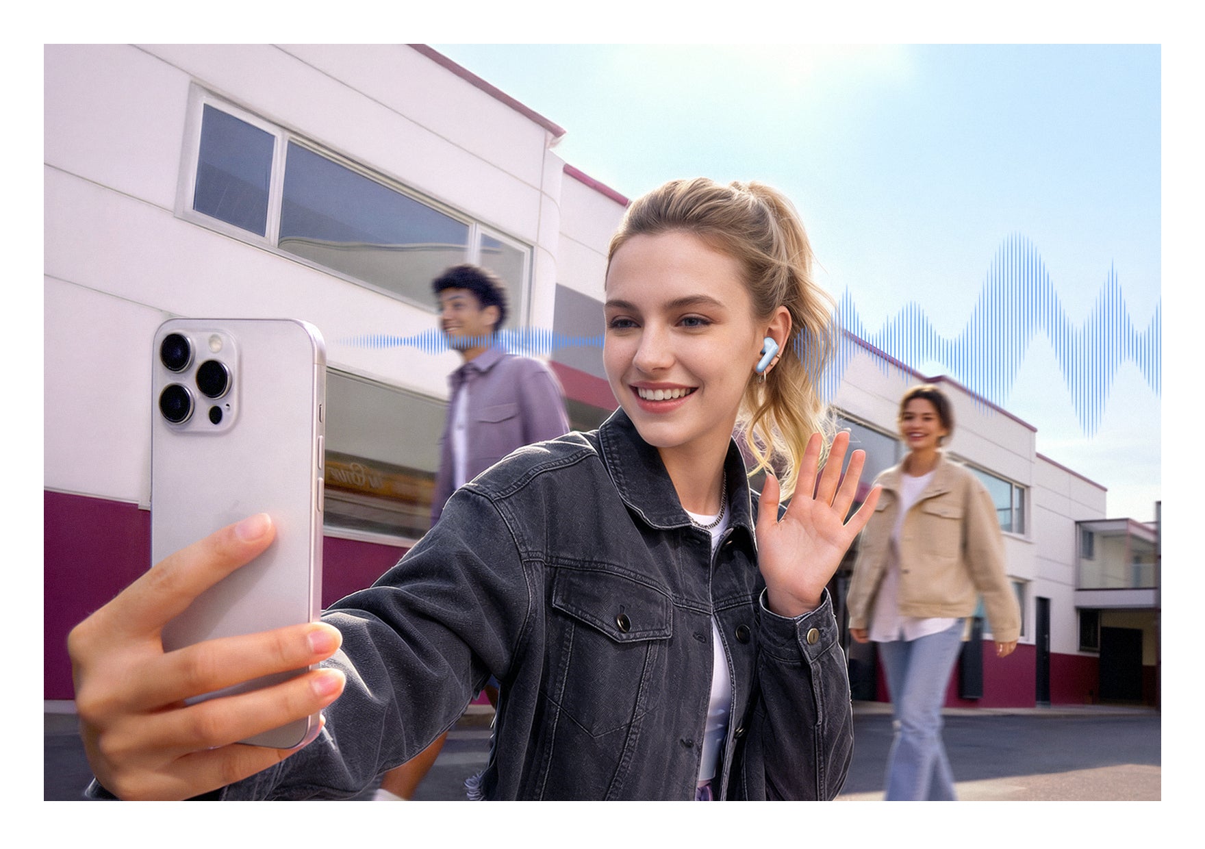 Donna con auricolari wireless che fa un selfie con lo smartphone, sullo sfondo amici e edifici